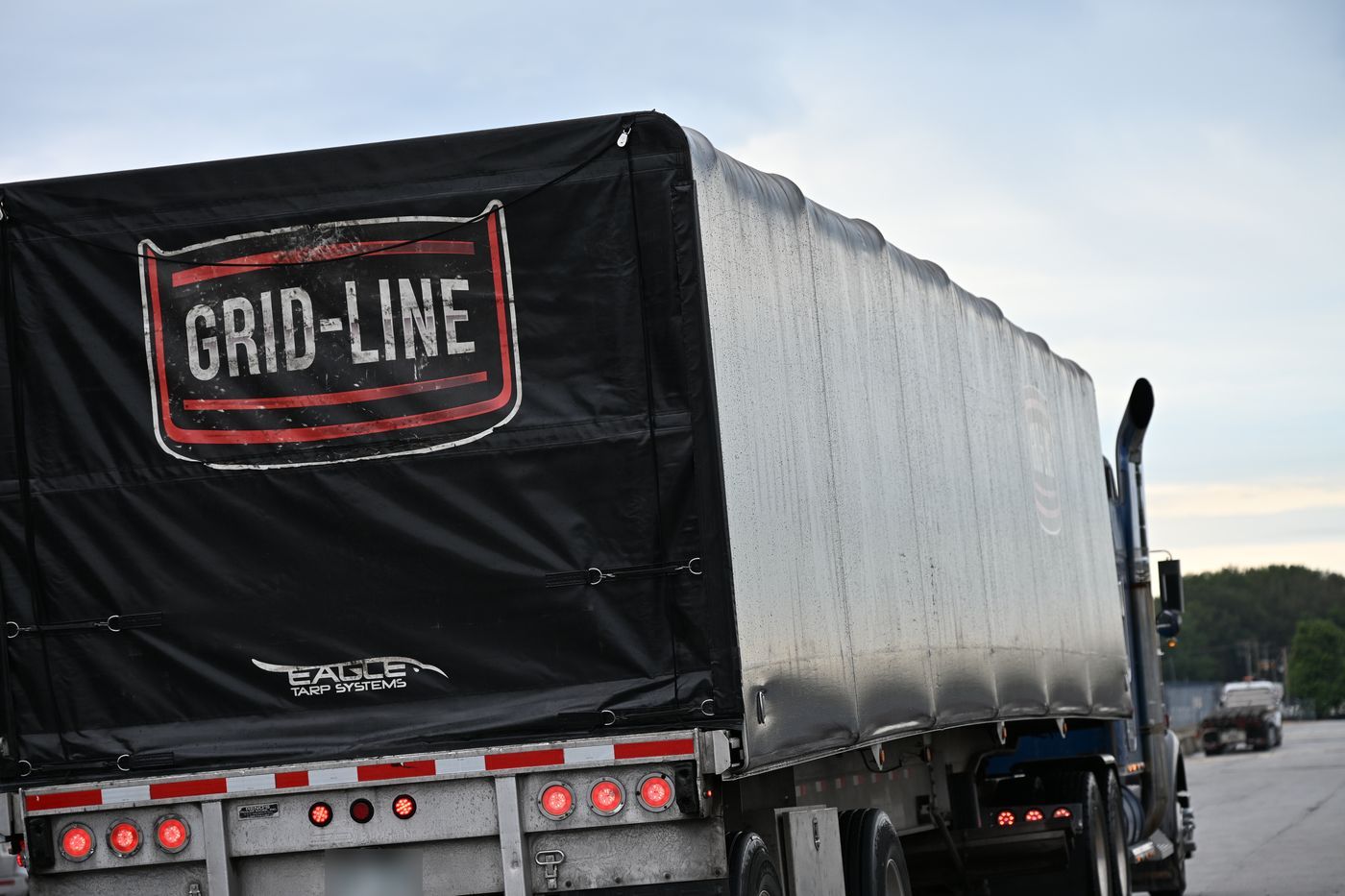 Rear of a Grid-Line conestoga trailer with the company logo