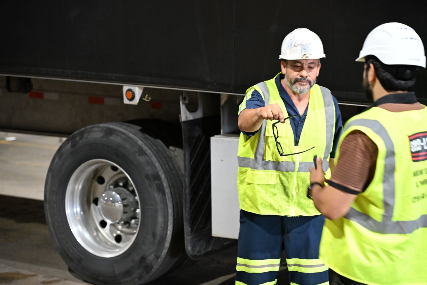Grid-Line crew in hard hats and hi-vis beside a loaded flatbed